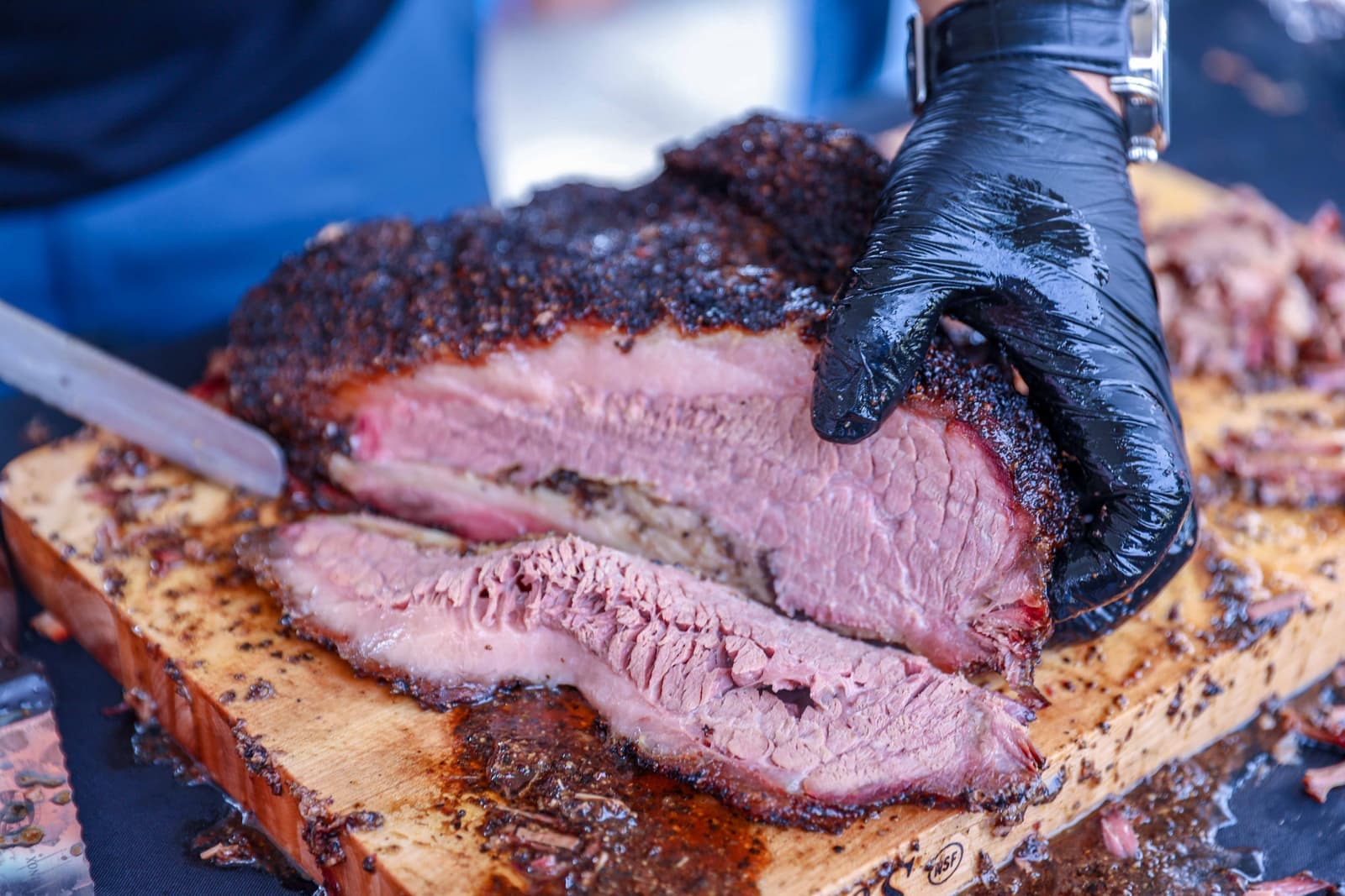 A sliced smoked brisket showing bark and a pink smoke ring on a wooden board