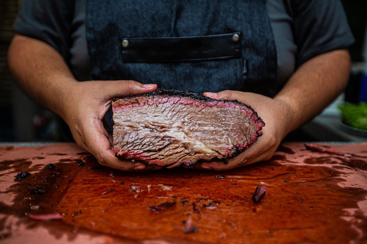 A brisket wrapped in pink butcher paper on a cutting board