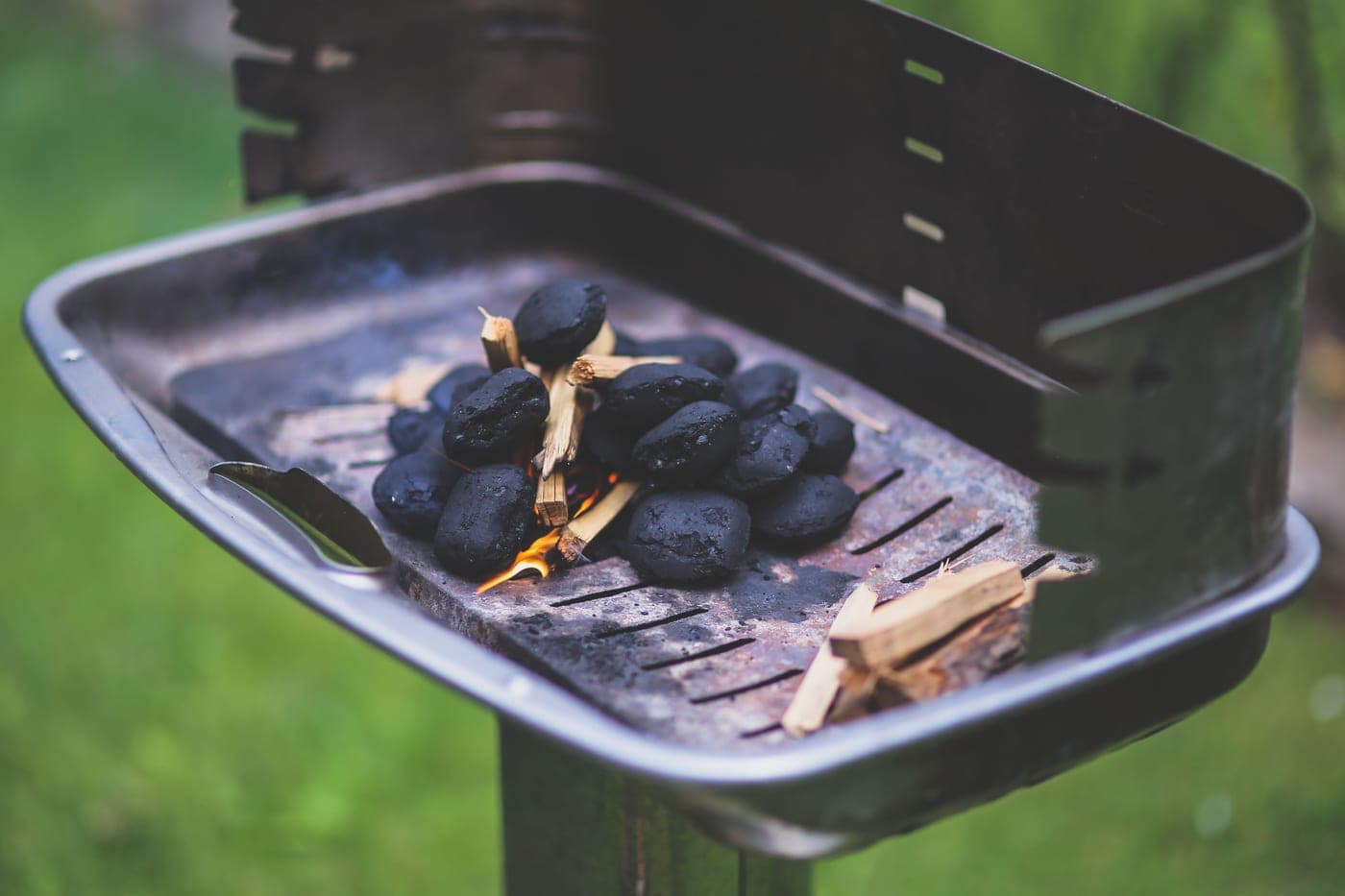 Split hardwood and glowing coals in a smoker firebox